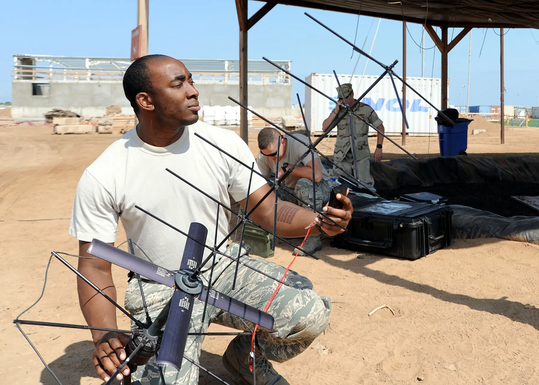 Technician assembling a portable tactical satellite antenna outdoors