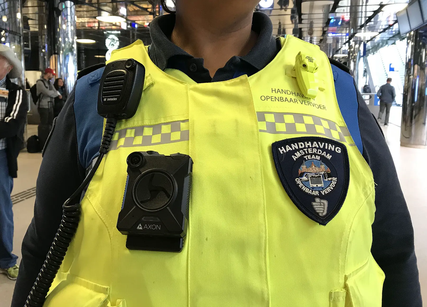 Enforcement officer wearing a yellow high-visibility vest with radio and body camera