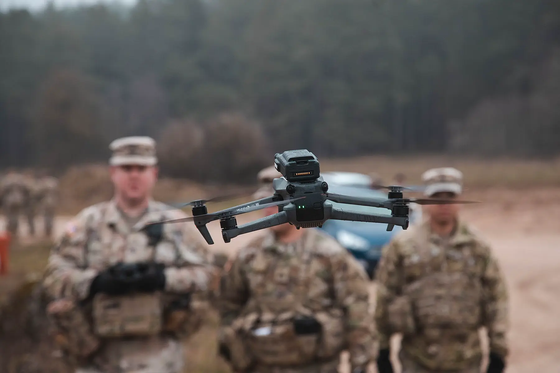 Compact quadcopter drone hovering in front of personnel during training