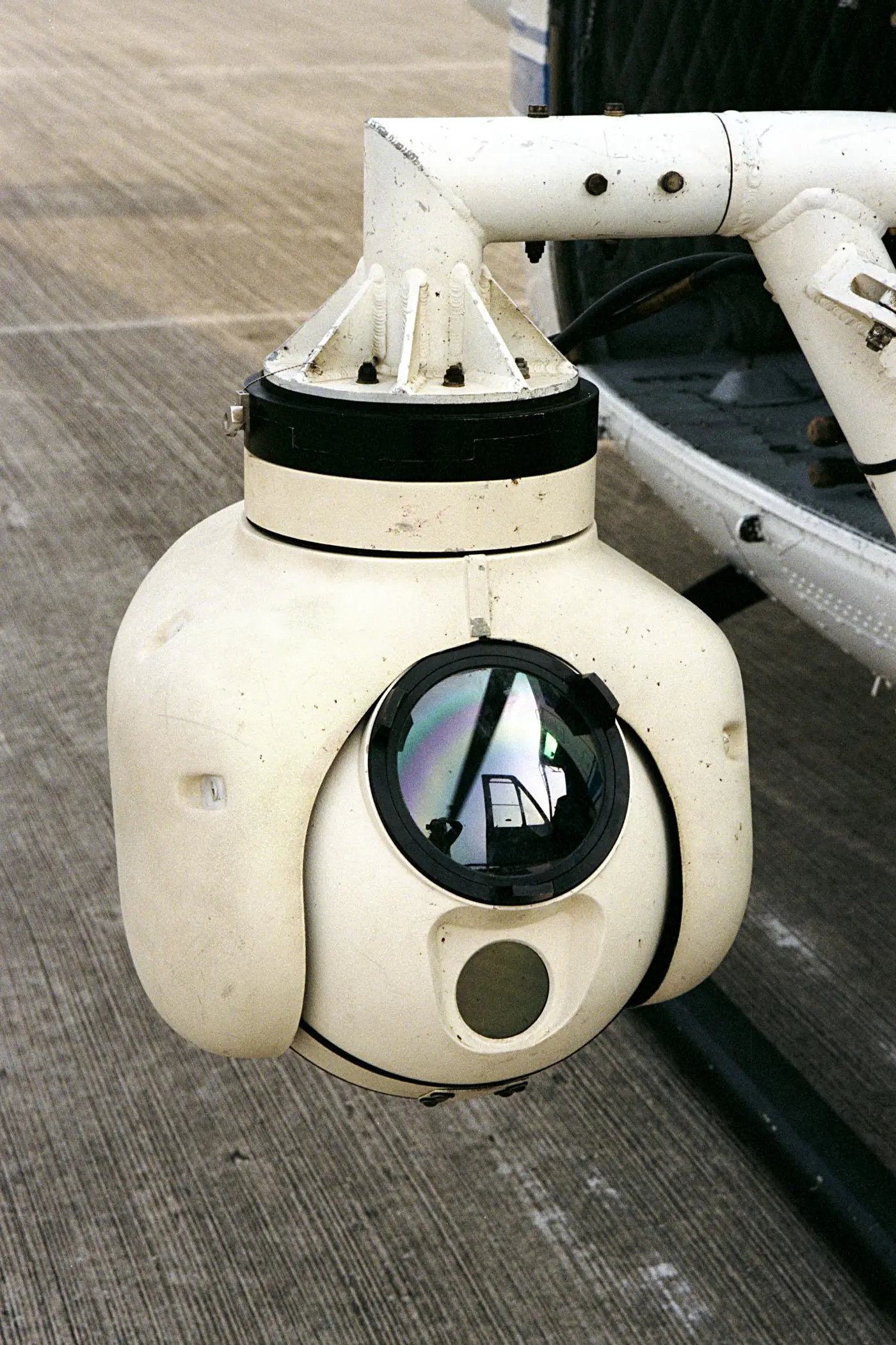White gimbal-mounted infrared camera turret fitted to the side of a helicopter